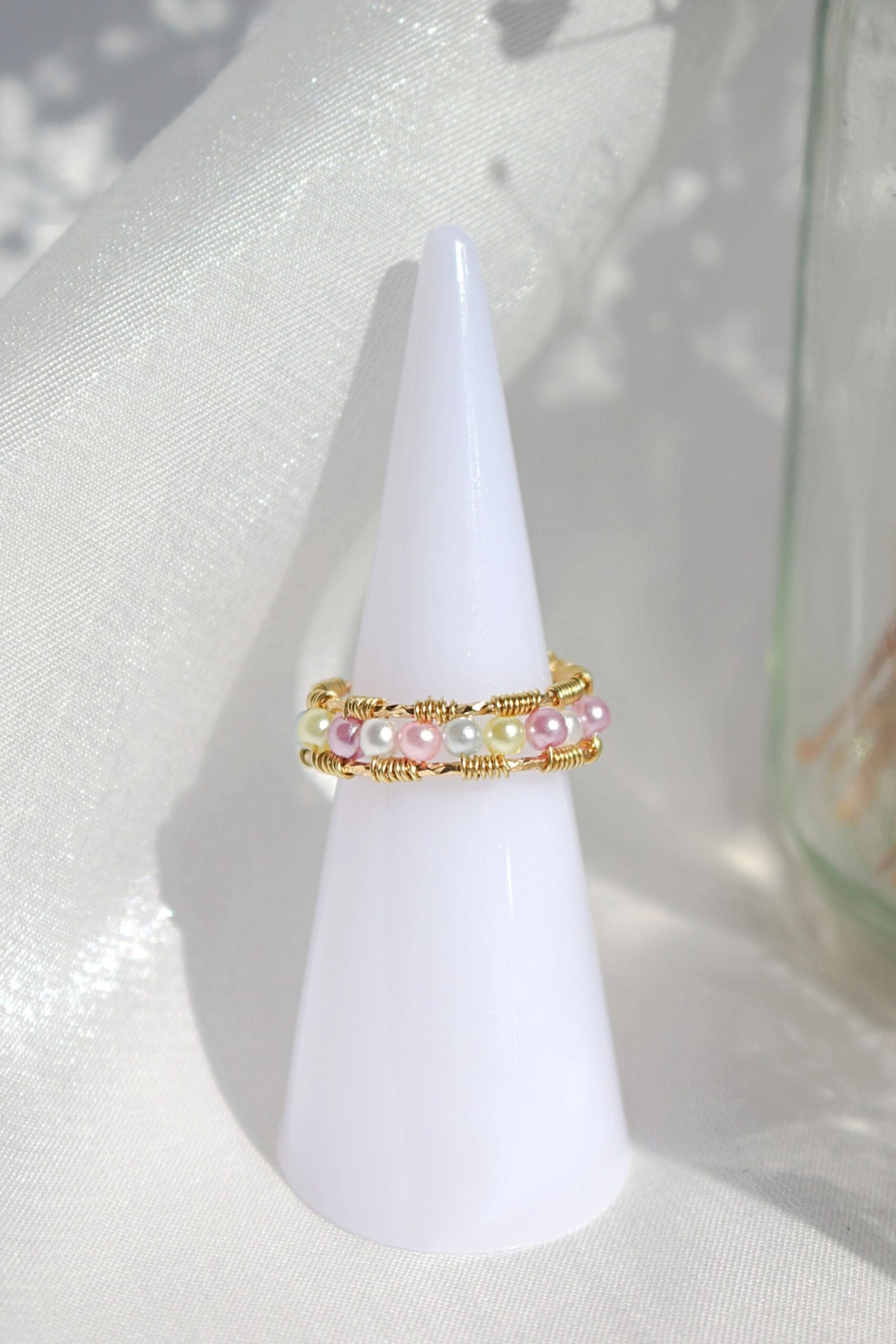 Anel artesanal com cristais em arco-íris pastel, feito à mão, com detalhes em dourado.