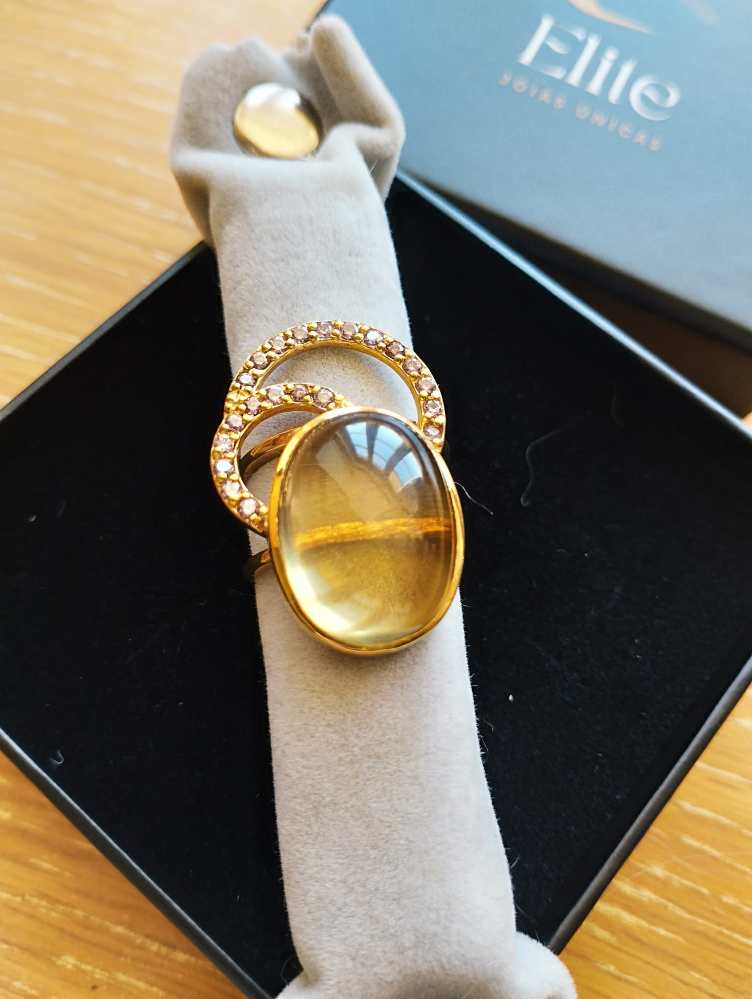 Anel ELITE dourado com pedra oval verde amarela e aro cravejado em estojo joia exclusiva Elite Anel Moon GreenGold